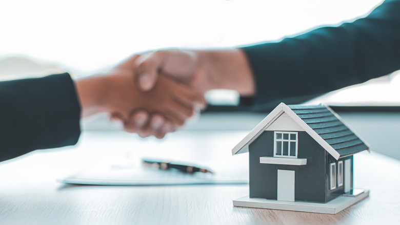 shaking hands near small house