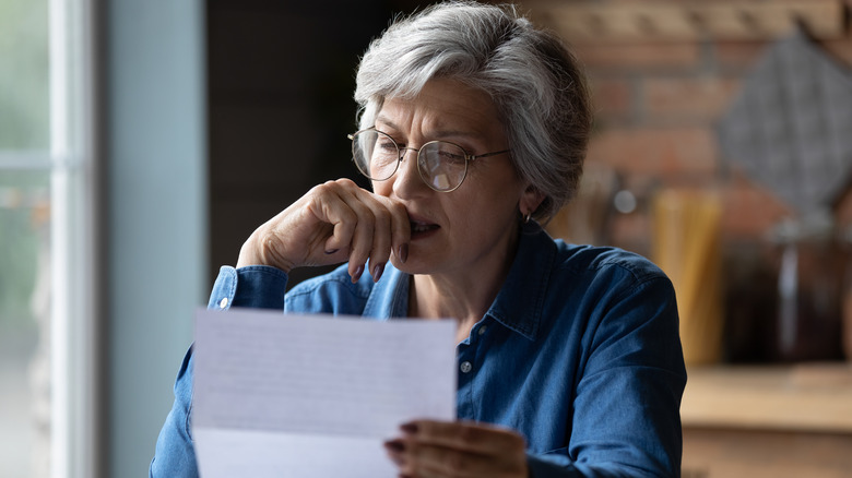 woman reading paper looking concerned