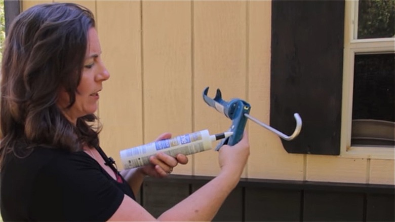 woman cutting caulk tube with caulk gun