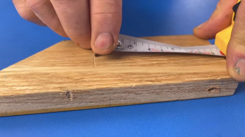 person marking wood with measuring tape