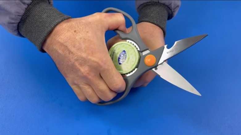 person opening jar with scissors