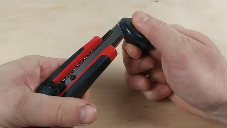 person snapping box cutter blade