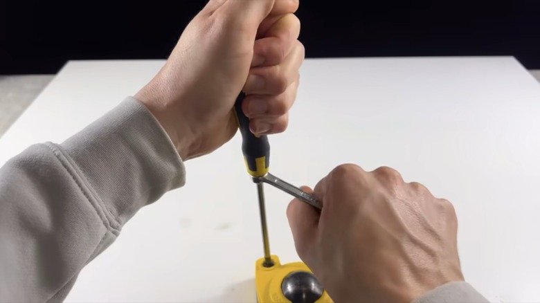 man turning screwdriver with wrench