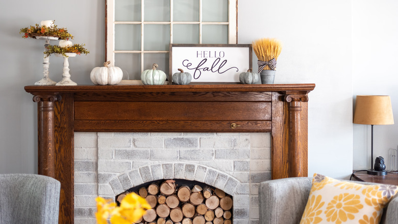 A mantel decorated for fall with candles and a pumpkin