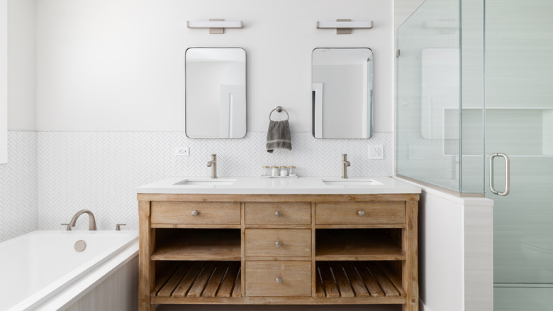 Timber bathroom vanity with double sinks and mirrors and a glass shower partition wall to the right