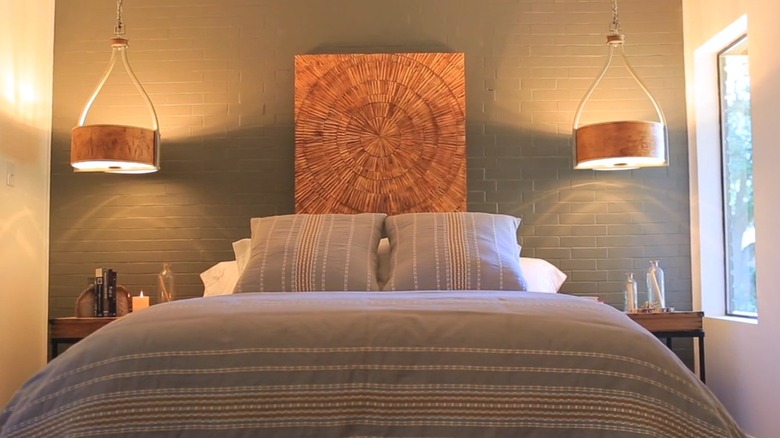 Brick accent wall behind bed with two hanging lights