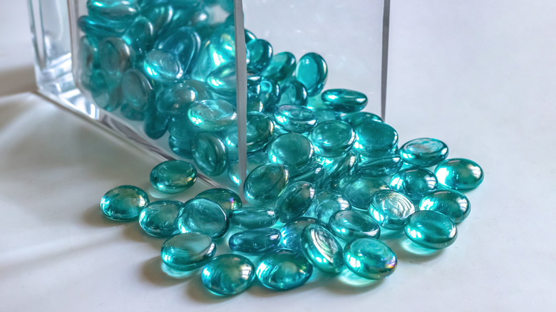 Blue glass gems spilling out of a square glass vase