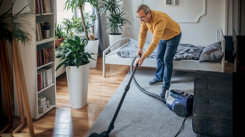 man vacuuming bedroom