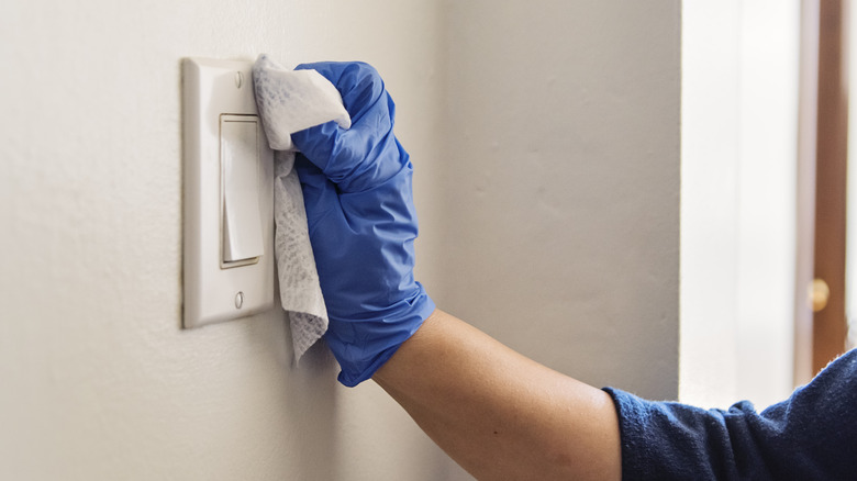 hand wiping down light switch