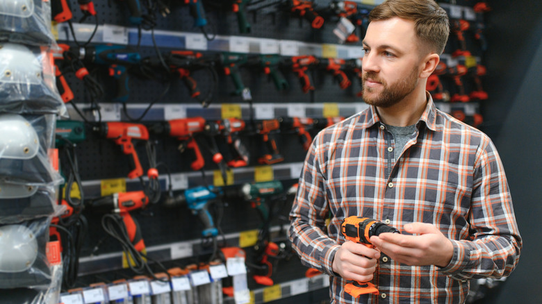 Man in checked shirt looking at tools in a hardware store