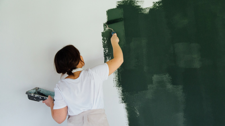 Woman painting a white wall green