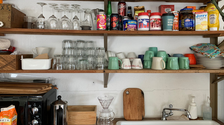 Cluttered open shelves over a kitchen sink