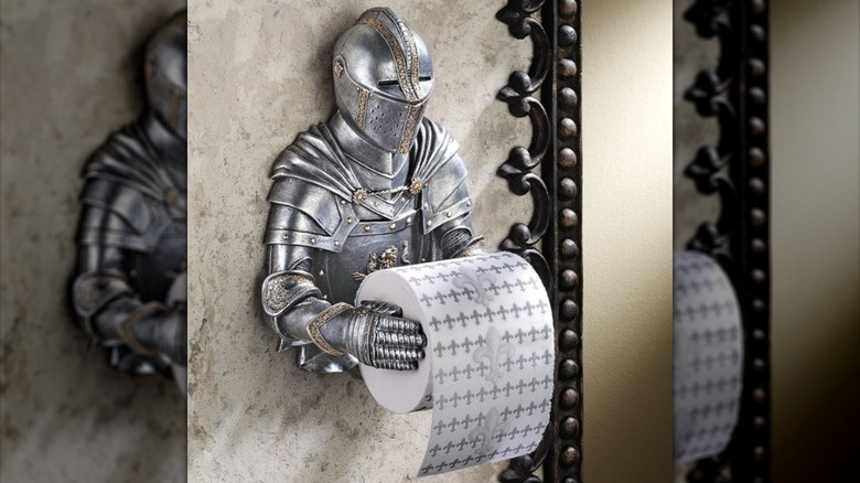 A medieval knight toilet paper holder in a bathroom next to a toilet