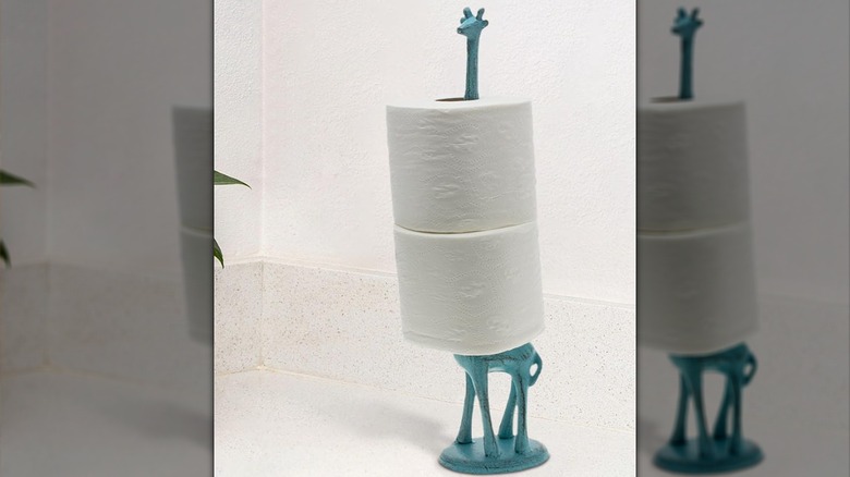 A giraffe with a long neck that serves as a toilet paper holder for a bathroom