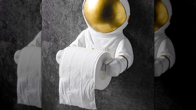 An astronaut figure with a gold visor that is a toilet paper holder