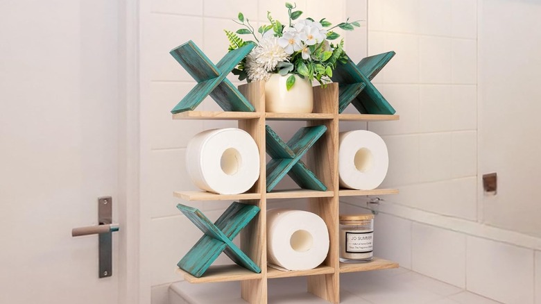 A rustic wooden tic tac toe-themed toilet paper holder on a bathroom counter