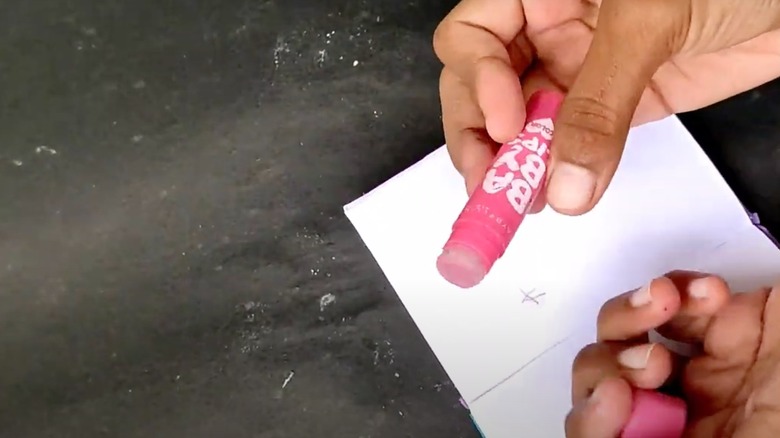 Woman twists up the eraser she inserted into an old lip balm container.