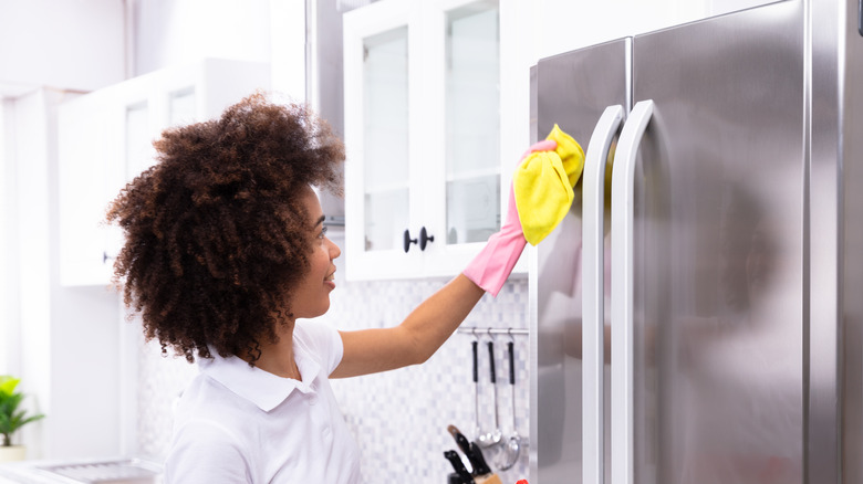 Woman wiping fridge exterior