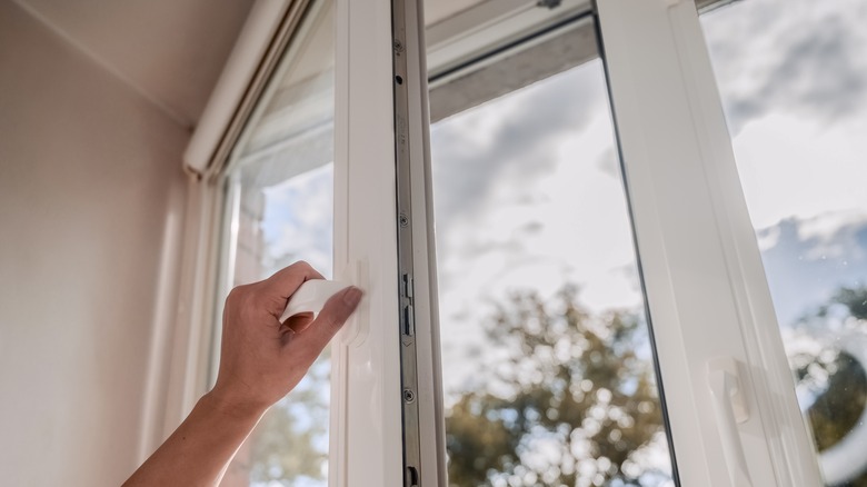 person's hand opening window