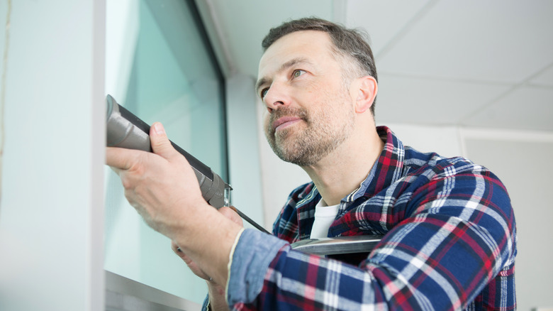 man caulking around window