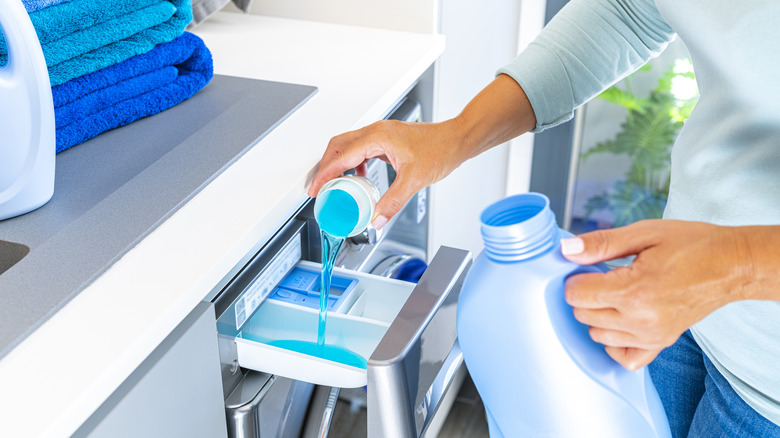 pouring laundry detergent in machine