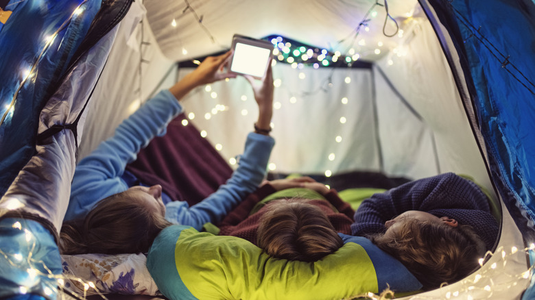 Kids laying in a camping tent with decorative string lights