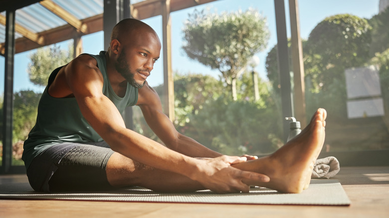 Man stretching in a greenhouse converted gym