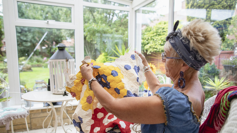 Woman knitting a quilt in a greenhouse studio