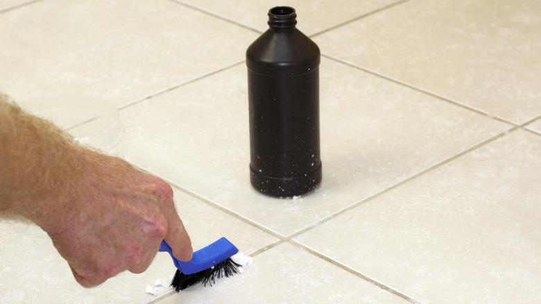 person cleaning tile grout with black bottle of hydrogen peroxide