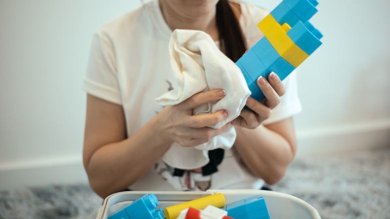 A person cleaning toy blocks with a cloth