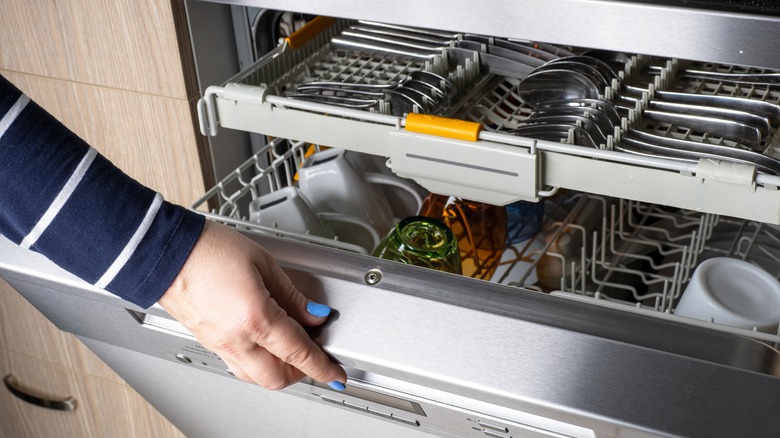 Woman's hand opening dishwasher