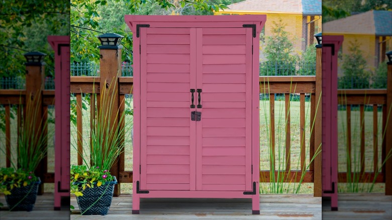 A small rose pink storage shed sits on a deck