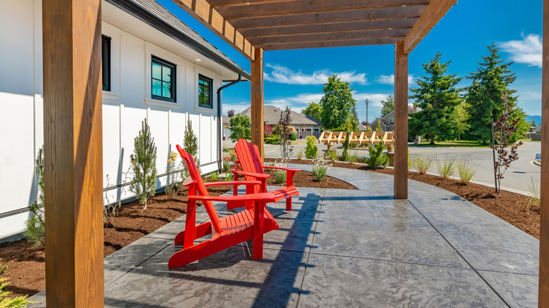 sunny stamped concrete patio with red Adirondack chairs