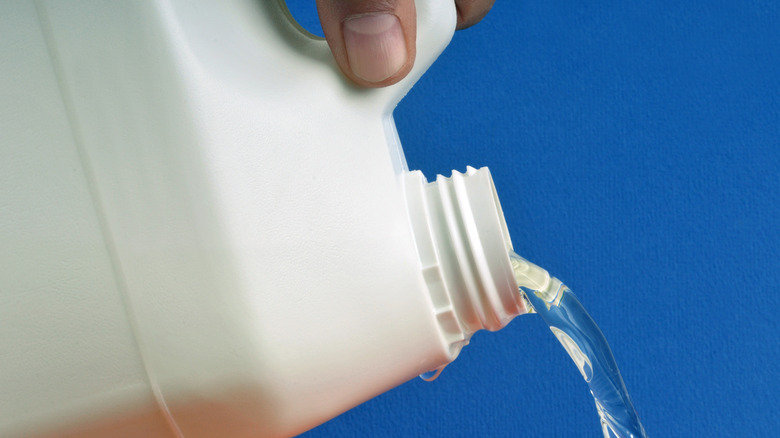 person pouring bleach from bottle