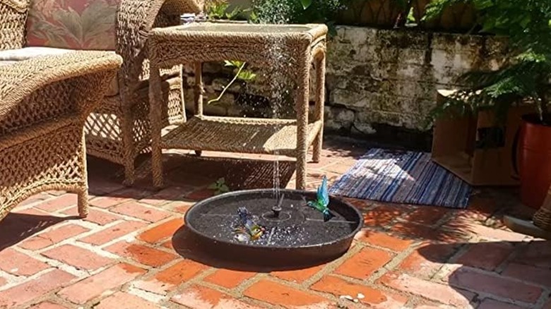 A plastic bird bath saucer in yard around outdoor furniture