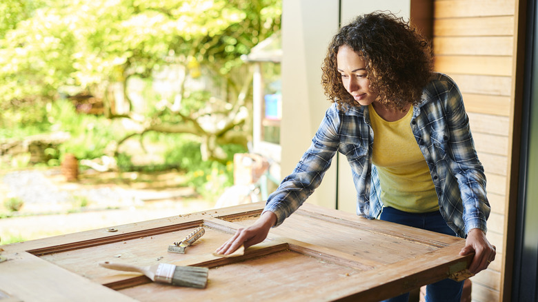 A person sanding salvaged closet door