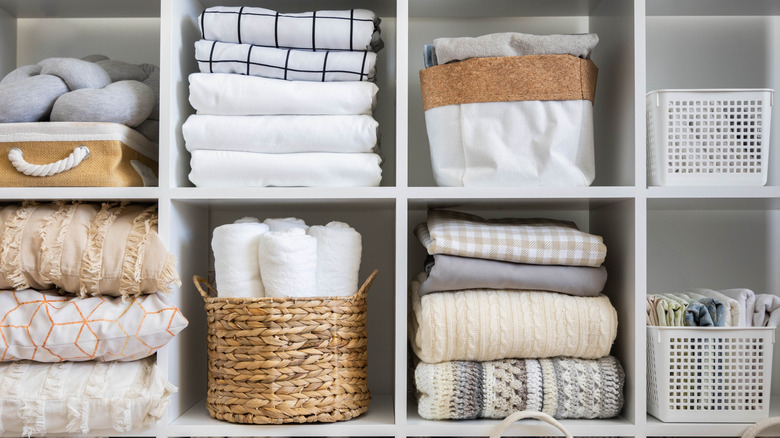 Decorative baskets storing linen on closet shelves