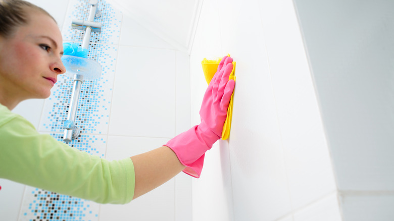 Person scrubbing bathroom tile