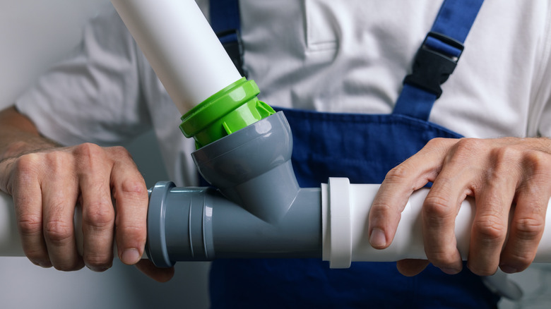 A plumber holding PVC pipes