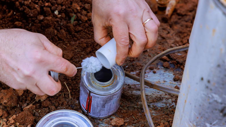 A plumber applying primer to a PVC pipe