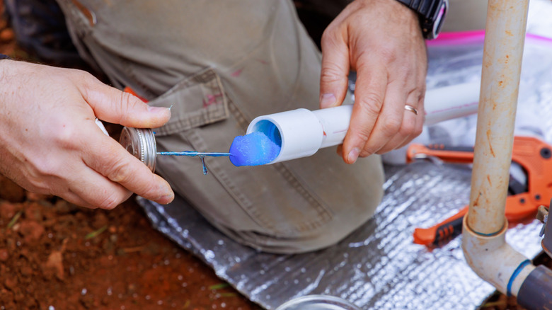 A person apply glue to a PVC pipe