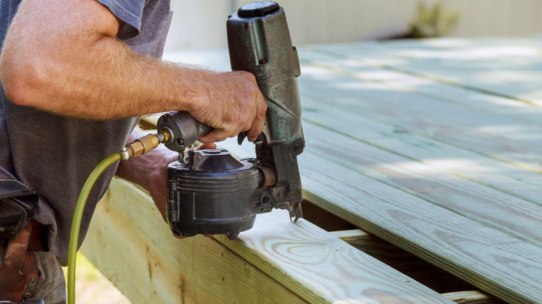 A person using a nail gun to install a deck