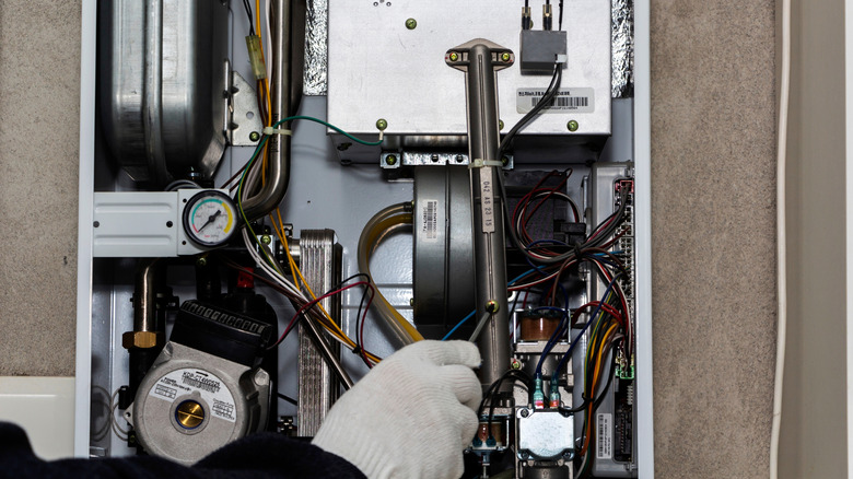 A gloved hand working on a furnace