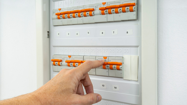 A person flipping a switch on the circuit breaker