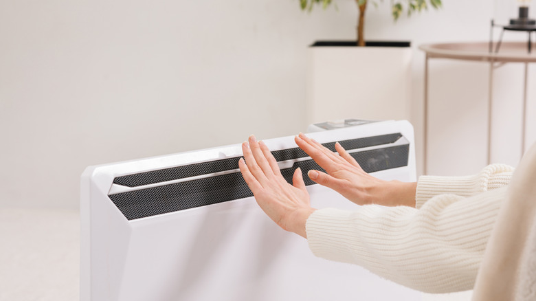 hands testing heat near furnace