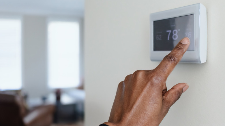 A person adjust the thermostat