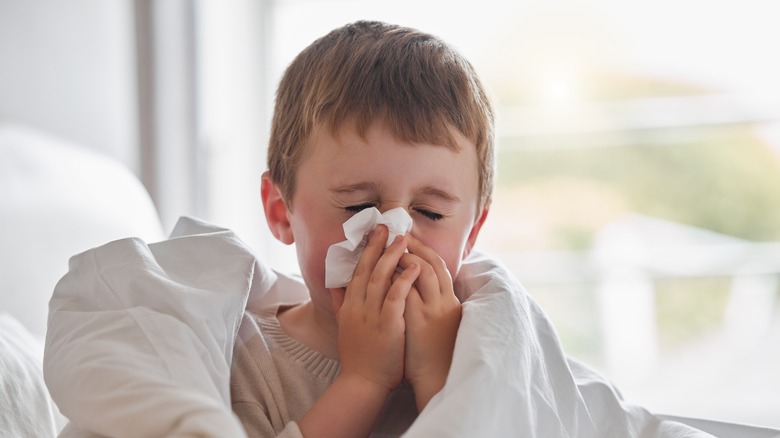 boy blowing his nose in bed