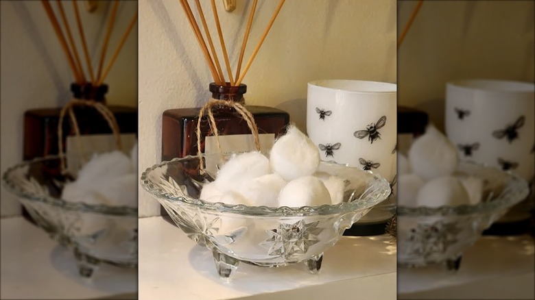 Glass bowl of cotton balls on a bathroom counter