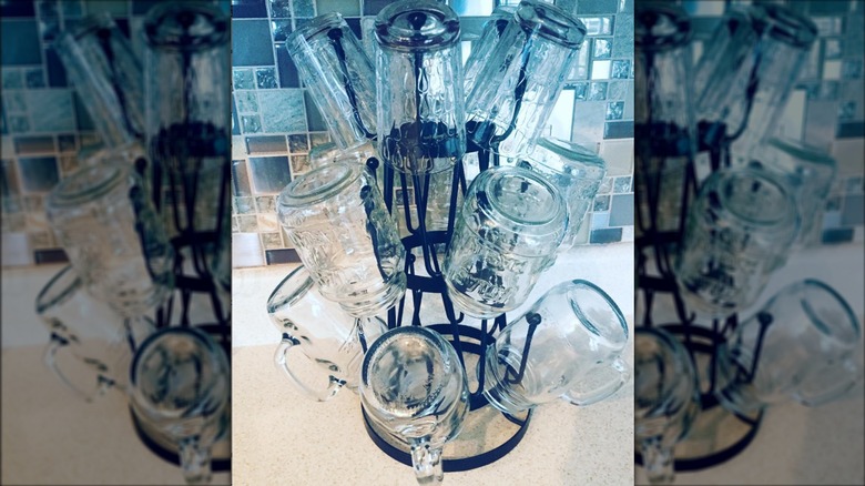 Glass jars and tumblers on mug rack