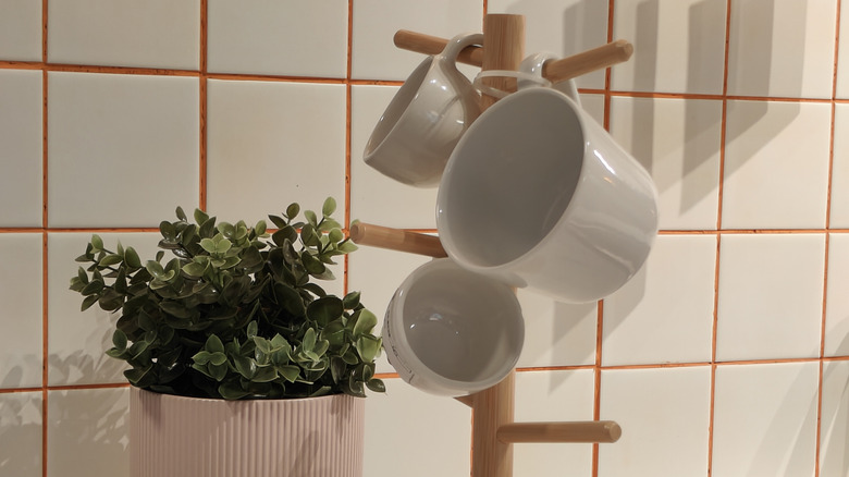 Coffee mug holder on counter with plant